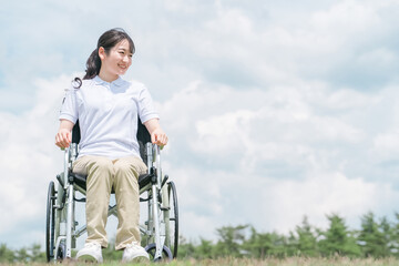 車椅子に座る笑顔の日本人女性（青空）
