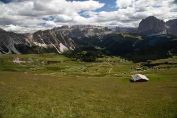Fototapeta na wymiar Mountain huts with the beautiful mountainous landscape of Val Gardena in Dolomites.