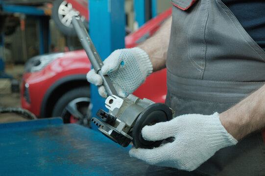 Repair of a passenger car at a car service station. An auto mechanic inspects the new steering column shaft. Quality control and compliance of the spare part before replacement.
