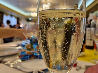 Close-up of a champagne glass with effervescent bubbles, foreground in focus with a celebratory...