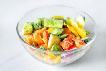 Frozen vegetables in a glass plate on a white background. The concept of healthy eating