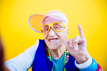 Funny grandmother portraits. 80s style outfit. trapstar taking a selfie on colored backgrounds. Concept about seniority and old people - 733637604
