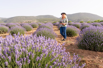 Young blonde woman walking in the lavender fields in Kuyucak region of Turkey