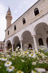 Alacati Pazaryeri mosque with flowers on the foreground, Turkey. Vertical orientation.
