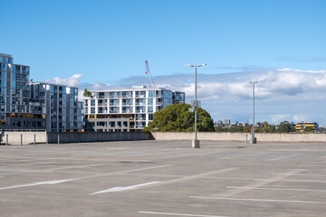 An empty rooftop parking lot with some residential apartment buildings in the background. Background texture of urban outdoor car park with many spaces but no car. Copy space for your design.