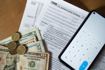 tax refund: Form 1040, money dollars and phone with open calculator on table