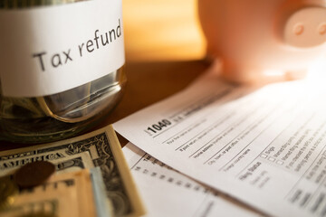 tax refund: piggy bank, money and Form 1040 on table