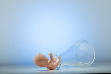 Figurine of a pupa on chemical test tubes. Concept of artificial insemination, test tube baby - obrazy, fototapety, plakaty
