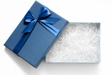 Open gift box with shredded paper on a white background. Blue cardboard box with decorative fillers for your product. Flat lay, top view, empty space for products