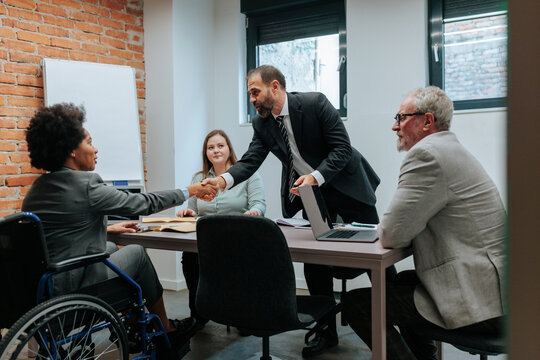 An Office worker in a wheelchair shaking hands with her CEO - Powered by Adobe