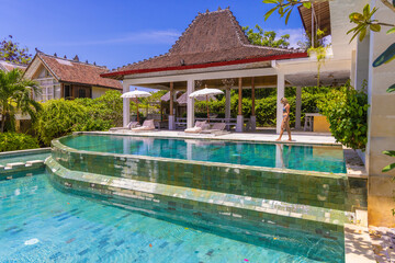 Fototapeta premium A young girl in a swimming pool in a resort in Uluwatu, Bali