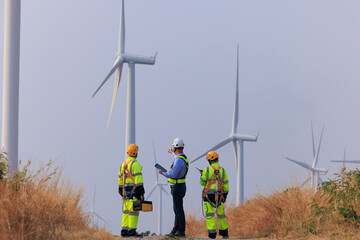 Engineer team hold equipment and tablet standing to talk planing project install wind turbines in the agricultural area. renewable energy installation project for the future world