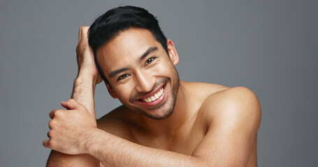 Face, cosmetics and Asian man with skincare, smile and dermatology on a grey studio background....