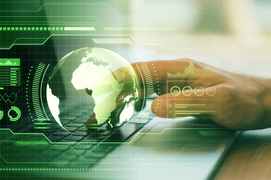 Close up of male hands using laptop at desk with holographic screen with digital globe interface and business chart on blurry green background. HUD, international stock and future monitor concept.