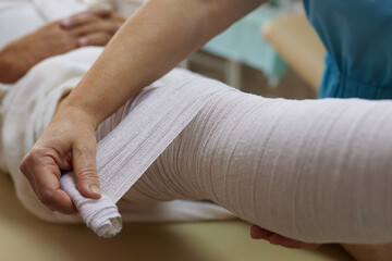 doctor bandages patient's leg in emergency room, leg injury - obrazy, fototapety, plakaty