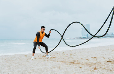 young athlete training in the morning on the beach with ropes - 733663009
