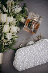 A modern composition of elegant wedding accessories for an attractive bride. Clutch engagement rings with pearls, wedding bouquets, perfume bottles. The bride is getting ready