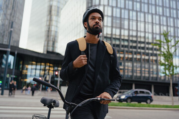 City commuter, businessman traveling from work to home on bike, wearing backpack and helmet for...