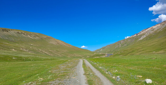 Mountain road along a beautiful plateau between mountain ranges. An untrodden path full of adventures and beautiful views.