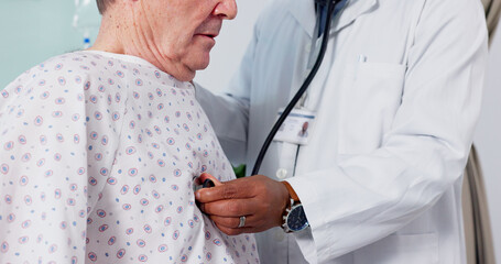 Senior man, doctor and breathing on stethoscope, checkup and consultation in hospital, health issue...