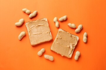 Tasty peanut butter sandwiches and peanuts on orange background, flat lay
