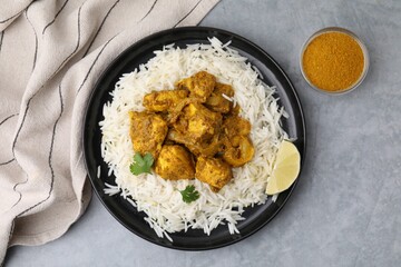 Delicious chicken curry with rice on grey table, top view