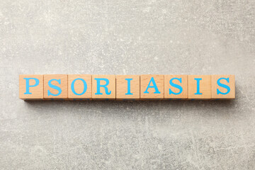 Word Psoriasis made of wooden cubes with letters on light gray textured table, top view