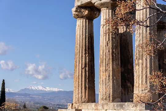 Doric colonnade Temple of Apollo in Ancient Corinth close up, with beautiful mountains and Peloponessian landscape at background. Corinth, Greece