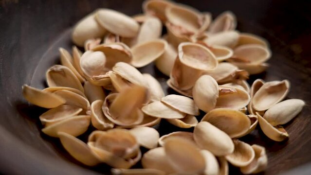 Separate waste collection concept. Organic biodegradable pistachio nushell falling in slow motion into a wooden bowl close up