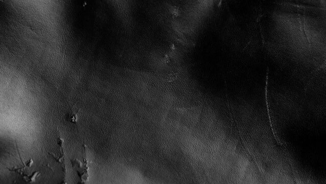 Black grunge background from scratched worn artificial leather close up. Rotation