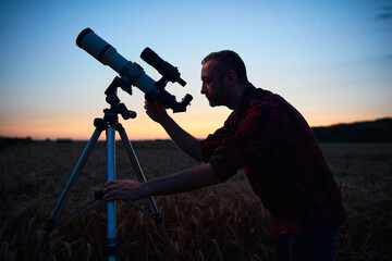 Astronomer looking at night sky with a telescope.