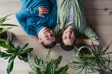 Portrait of young man with Down syndrome with his mother at home, lying on floor. Concept of love...