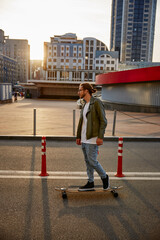 Hipster skateboarder enjoying extreme sport riding in urban park square