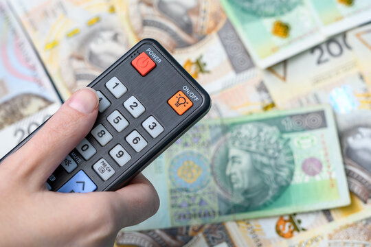 Oglądać telewizje, trzymac w dłoni pilot nad banknotami