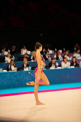 Rhythmic gymnastics in the professional arena. Performance with colored maces in front of the audience and judges