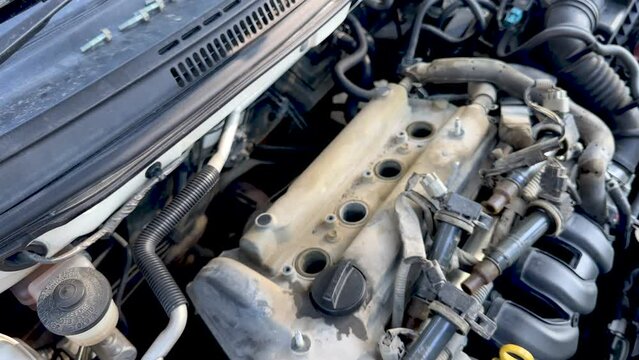 Mechanic's hand tightens nut on newly installed ignition coil on a car engine