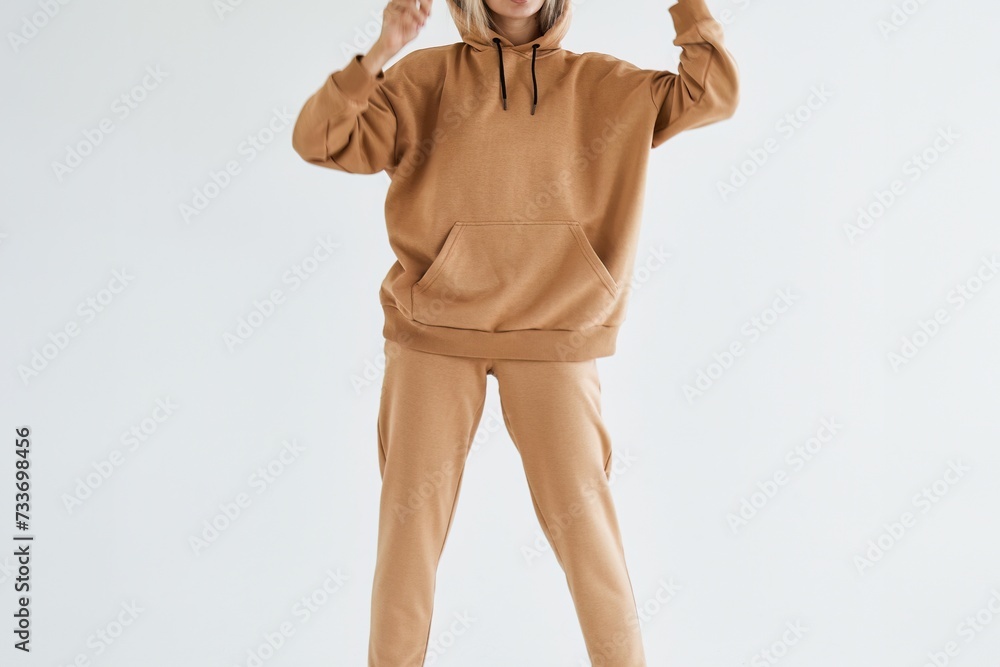 Wall mural Front view of a Woman wearing a hoodie. Horizontal studio photo on white neutral background. Girl posing in blank sweatshirt. - Wall murals