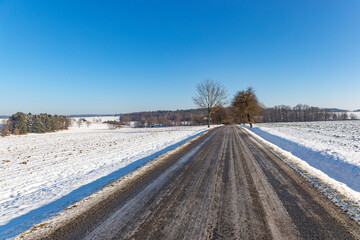 Fototapeta na wymiar Snowy and frozen road in winter landscape.