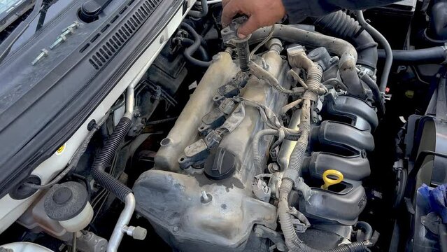 Auto mechanic testing and checking ignition coils of a car engine