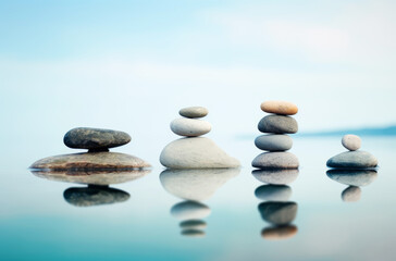 Fototapeta na wymiar Balanced stone stacks on tranquil water surface reflecting peace and mindfulness