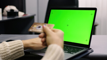 Close-up of a beautiful European girl taking a credit card to fill out card information Sitting online shopping through a laptop to use a credit card to pay online.