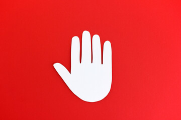 Stop Hand - No means no - Paper cutout of white stop gesture in shape of hand on bright red...