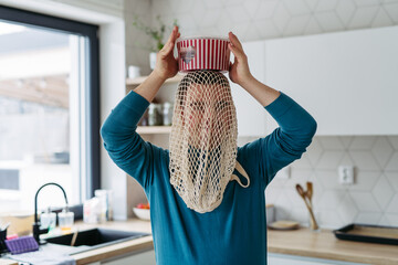 Portrait of young man with Down syndrome being funny, have mash net bag on head, holding popcorn.