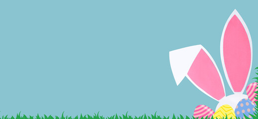 Easter background with rabbit ears and eggs on a blue background. Easter concept. Copy space. Banner