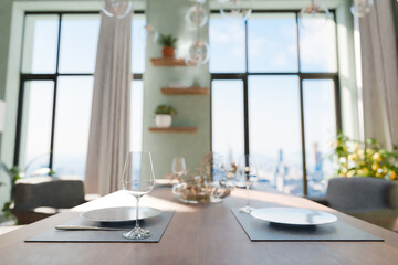 closeup of dining table in luxurious loft apartment with floor-to-ceiling windows and panoramic view; modern minimalistic interior design; bright daylight; 3D rendering