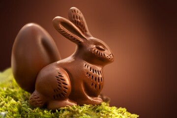 Small chocolate bunny with eggs sitting on green grass