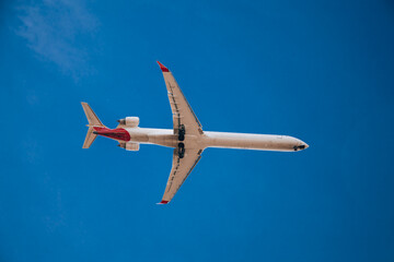 Passenger plane in flight. Bottom view of a red passenger plane flying above the clouds.