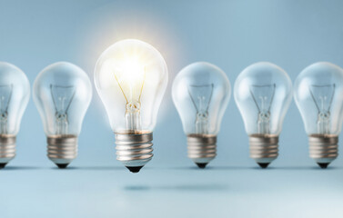 Light bulb bright outstanding among lightbulbs on Blue background