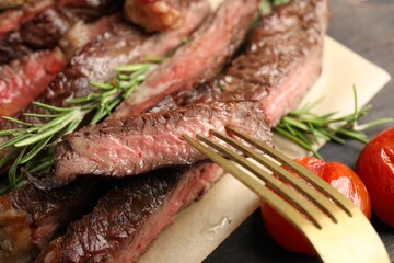 Fork with delicious grilled beef on table, closeup