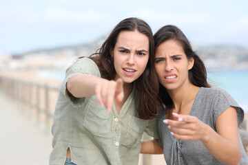 Upset women pointing at you on the beach